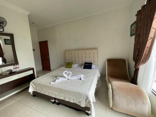 a bedroom with a bed and a chair at Urbanview Resort Syariah Khansa Cisarua Puncak by RedDoorz in Tagalbato