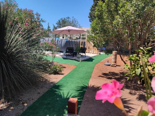 a garden with green grass and a patio with an umbrella at Villa Mary in San Pietro in Bevagna