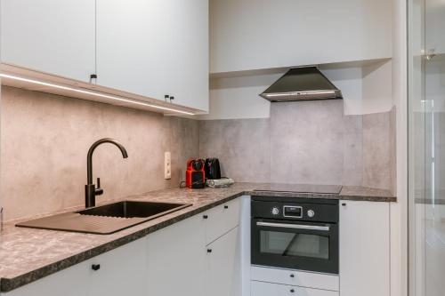 a kitchen with white cabinets and a sink at Huswell - Bright & Stylish Apartment with Balcony in Knokke-Heist