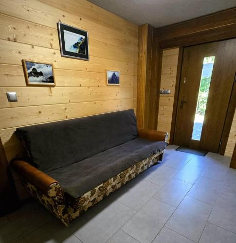 a couch in a room with a wooden wall at Górska Przygoda in Koniaków