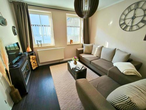 a living room with a couch and a clock on the wall at Apartment Kapstadt Garten & Poolnutzung als Extra möglich in Mühlhausen