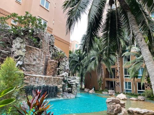 ein Wasserfall in einem Pool in einem Hotel mit Palmen in der Unterkunft Atlantis Condo Resort Pattaya in Jomtien Beach