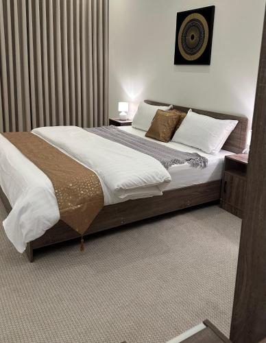 a bedroom with a large bed with white sheets and pillows at شقة بغرفة نوم وصالة in Buraydah