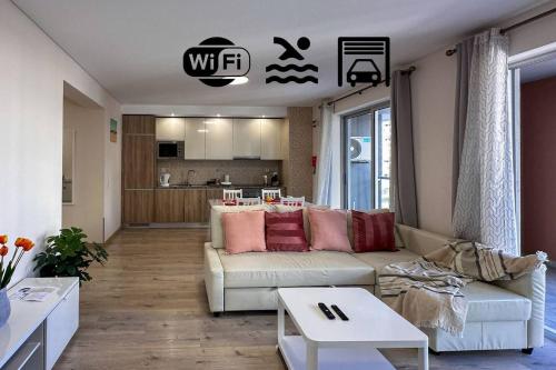 a living room with a white couch and a kitchen at Ed Elite 3F Apartamento a 5 min a pé da Praia da Rocha com piscina e garagem in Portimão