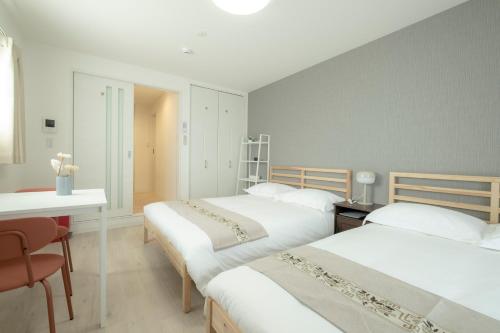 a bedroom with three beds and a table and a desk at GuesthouseA in Osaka