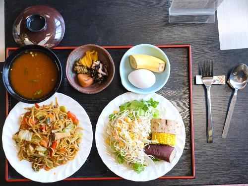 a table with two plates of food and a bowl of soup at 旅館青柳 海越し立山連峰の雪山絶景で休もう in Himi