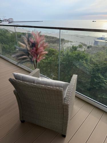 a chair on a balcony with a view of the ocean at Solaris Darłówko Premium Emilia Strupiechowska in Darłowo