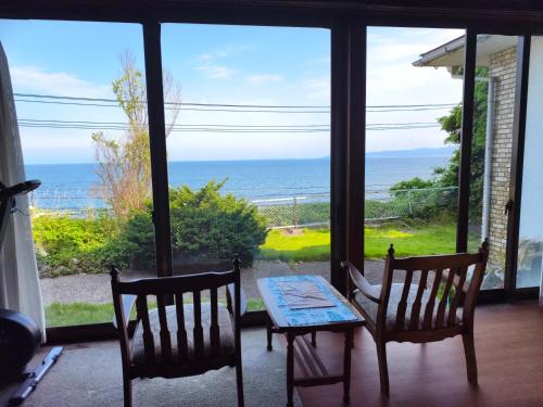 a table and chairs in a room with a view of the ocean at 旅館青柳 海越し立山連峰の雪山絶景で休もう in Himi