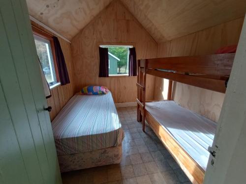 a bedroom with two bunk beds in a tiny house at Danseys Pass Holiday Park in Oamaru