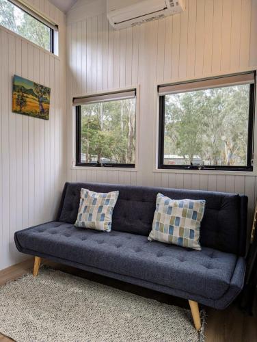 a blue couch in a room with two windows at Tiny Homes Escape at Grampians Edge by Tiny Away in Dadswells Bridge