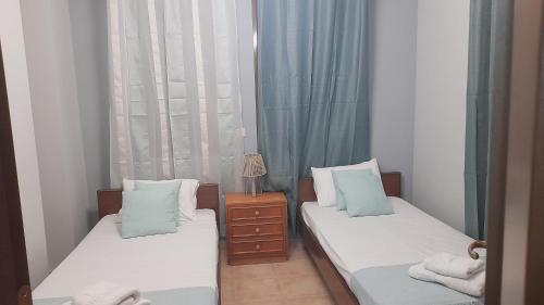 two beds in a small room with blue curtains at Andreadis maissonette in Skala Potamias