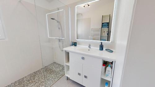 Un baño blanco con lavabo y espejo. en Oceana de l Isle de Riez, en Saint-Hilaire-de-Riez