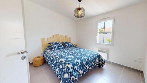 Un dormitorio con una cama con un edredón azul y blanco. en Oceana de l Isle de Riez, en Saint-Hilaire-de-Riez