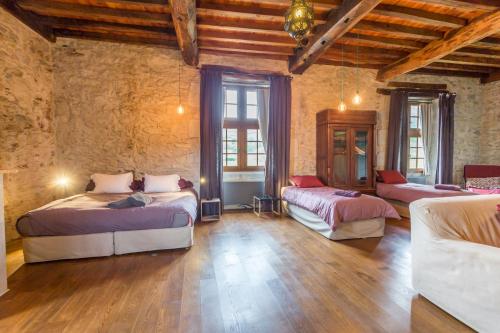 a large room with three beds and two windows at Les Fous du Village in Saint-Esteben