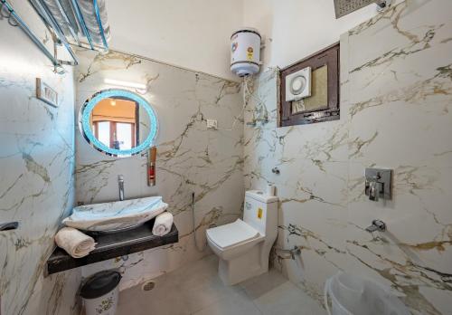 a bathroom with a toilet and a sink and a mirror at Hotel Sun Ray Inn in Bhowāli