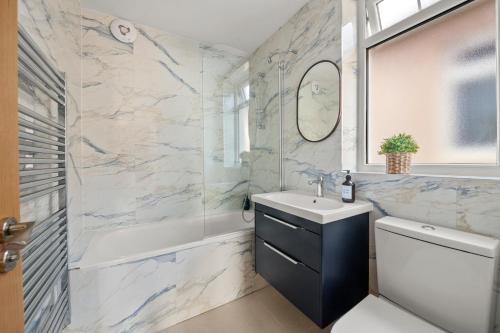a bathroom with a sink and a tub and a toilet at Stylish London Flat I Free parking in Harrow
