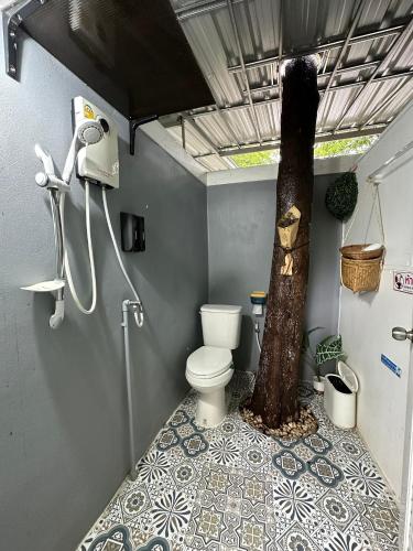 a bathroom with a tree next to a toilet at Nunou Cafe in Ban Than Lao
