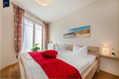 1 dormitorio con cama blanca y manta roja en Ferienwohnung Pretzer, en Ostseebad Koserow