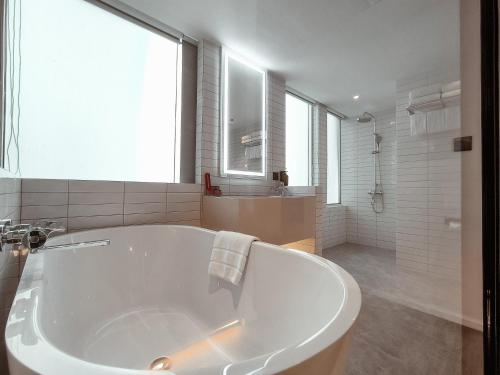 a large white tub in a bathroom with a window at Citrus Sukhumvit 13 Nana Bangkok by Compass Hospitality - Newly Renovated in Bangkok