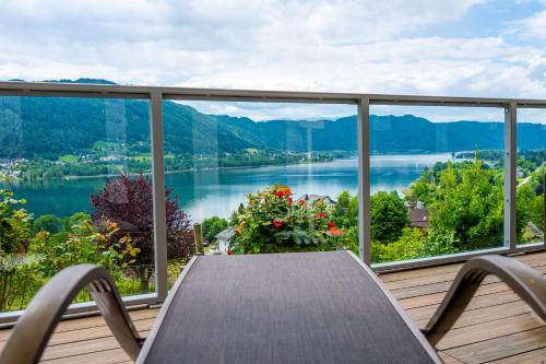 a balcony with a table and a view of a lake at Hotel Ossiacher See in Stiegl