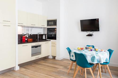 Il comprend une cuisine avec une table et des chaises ainsi qu'une télévision. dans l'établissement #28 1 BDR Flat AC Balcony Hper Central 10mins to Beach & old town, à Nice
