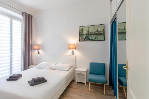 - une chambre avec un lit blanc et deux chaises bleues dans l'établissement #28 1 BDR Flat AC Balcony Hper Central 10mins to Beach & old town, à Nice