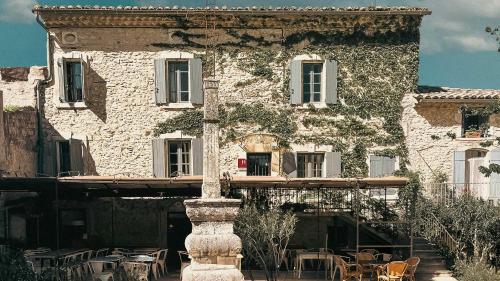 a stone building with tables and chairs in front of it at Maison Gramme Lussan in Lussan