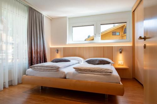 two beds in a room with two windows at Dolce Vita in Saas-Fee