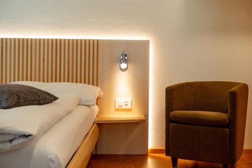 a bedroom with a bed and a chair and a light at Dolce Vita in Saas-Fee