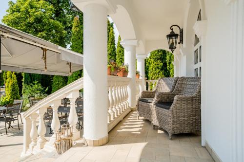 a white porch with wicker chairs and an arbor at Prémium Panzió Miskolctapolca in Miskolctapolca