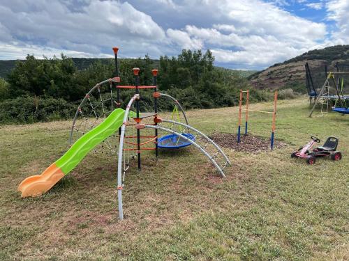 an outdoor playground with a slide and swings at Gites au Cœur de la Nature, Piscine et Vue sur le Lac du Salagou in Le Puech