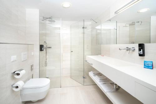 a white bathroom with a toilet and a shower at Hotel Parentium Plava Laguna in Poreč