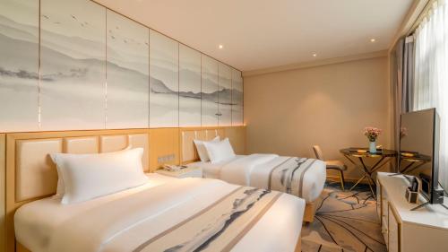 a hotel room with two beds and a tv at Weilai J Hotel Kunming New Luoshuiwan Branch in Kunming