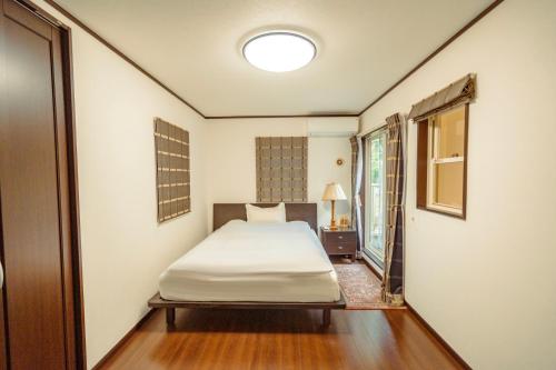 a small bedroom with a bed and a window at 箱根 森の風を感じる一軒家 in Hakone