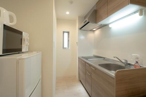 a kitchen with a sink and a refrigerator at GuesthouseA in Osaka