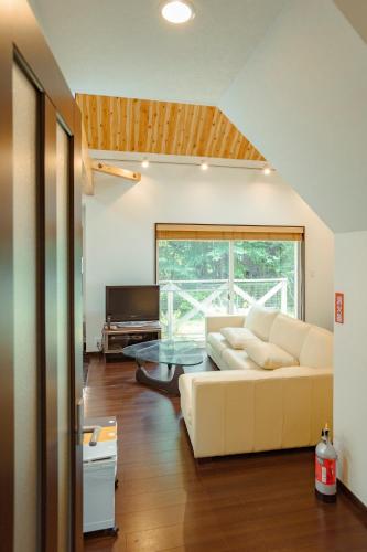 a living room with a white couch and a glass table at 箱根 森の風を感じる一軒家 in Hakone