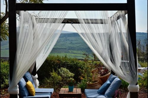 a gazebo with white curtains and a view at מול כנרת בליבנים in Livnim