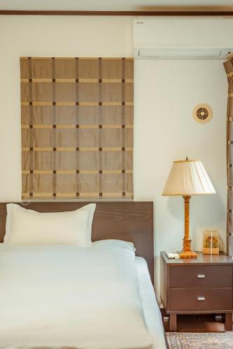a bedroom with a bed and a table with a lamp at 箱根 森の風を感じる一軒家 in Hakone