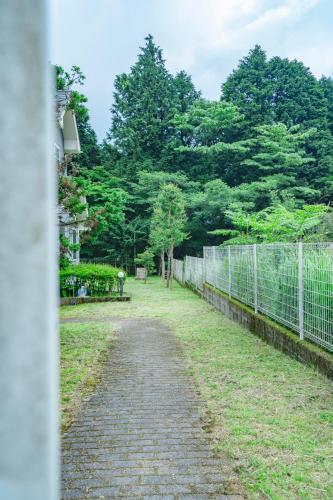 a brick path next to a fence and trees at 箱根 森の風を感じる一軒家 in Hakone