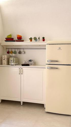 a kitchen with white cabinets and a white refrigerator at Palazzo Ammicc in Bernalda