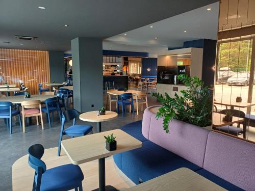 a restaurant with tables and chairs and a purple couch at Desilva Inn Katowice Airport in Pyrzowice