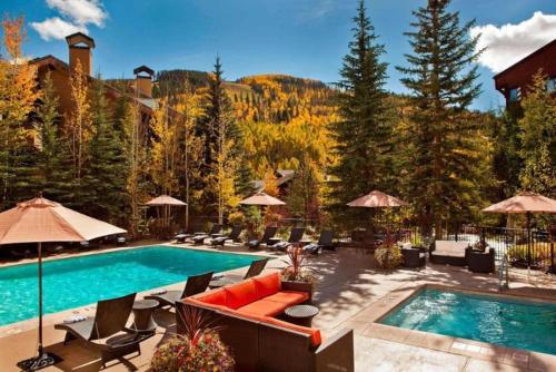 a swimming pool with chairs and umbrellas in a resort at Luxury 1 Bedroom At The Hythe In Lionshead Village in Vail