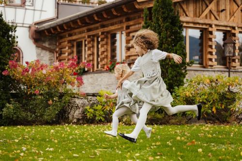 two children are running in the grass in front of a house at Hotel Spielmann in Ehrwald