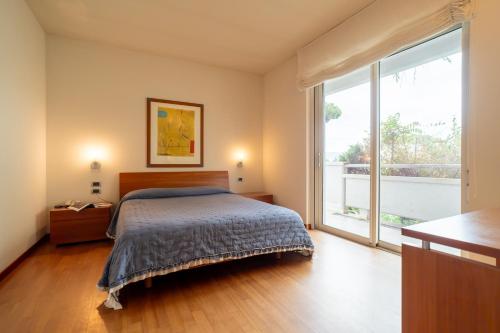 a bedroom with a bed and a large window at Verdeluna ApartHotel in Marina di Pietrasanta