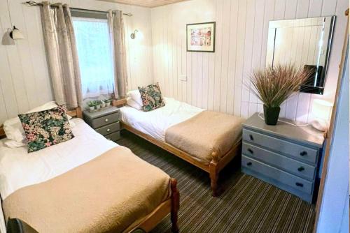 a bedroom with two beds and a dresser and a mirror at Beech Lodge 4 Hot Tub in York