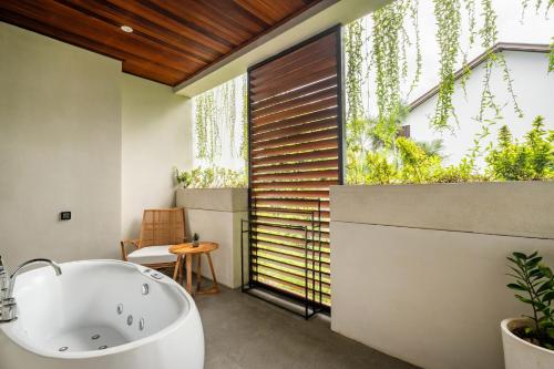 ein Badezimmer mit Badewanne und großem Fenster in der Unterkunft Alex Villas Complex N3 in Canggu
