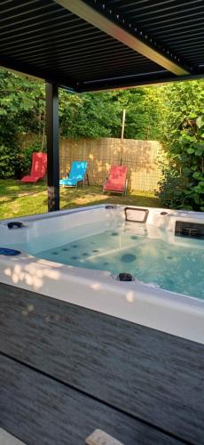 a hot tub in a backyard with two chairs at Le Jardin D' Épicure in Oderen