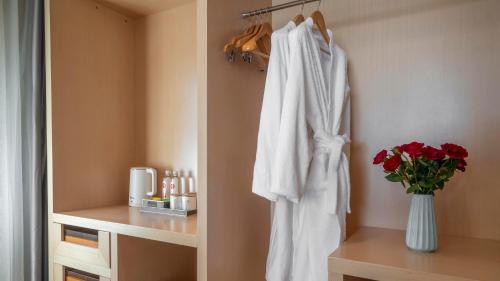 a bathroom with a white robe and a vase of flowers at Weilai J Hotel Kunming New Luoshuiwan Branch in Kunming