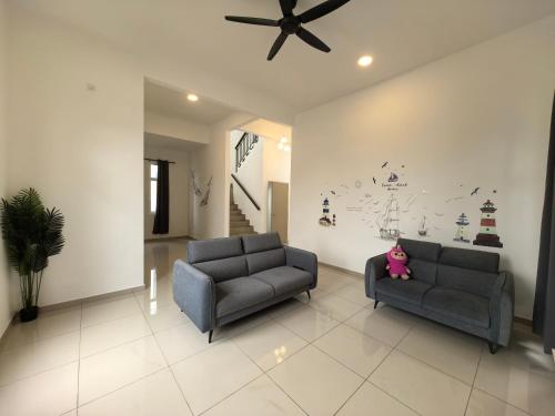a living room with two couches and a ceiling fan at Padang Serai Wangi Roomstay 95 in Padang Serai