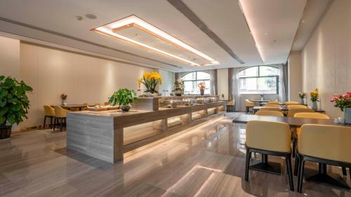 a restaurant with yellow chairs and a bar at Weilai J Hotel Kunming New Luoshuiwan Branch in Kunming